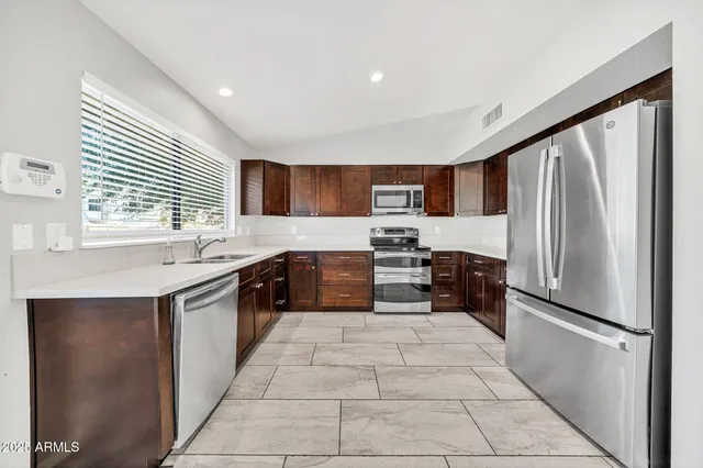 a kitchen with stainless steel appliances granite countertop a refrigerator stove top oven and sink