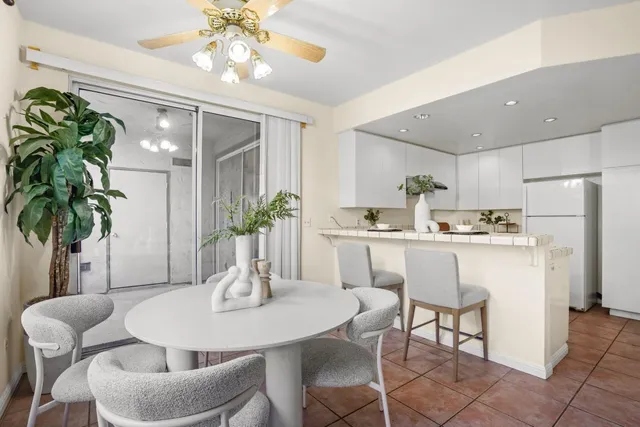 a dining room with furniture a potted plant and a kitchen view