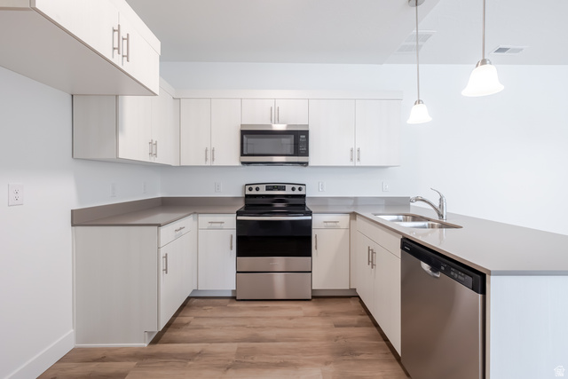 693 West 4500th South, Unit O304 Mapleton, UT 84664 - Photo 11 of 16 Kitchen featuring stainless steel appliances, a peninsula, light wood-style flooring, pendant lighting, and white cabinets