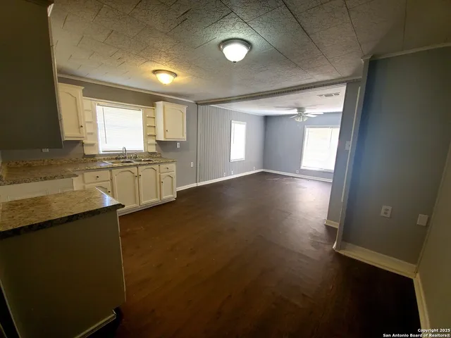 a view of an empty room with window and wooden floor