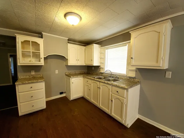 a kitchen with granite countertop a stove a sink dishwasher and white cabinets with wooden floor