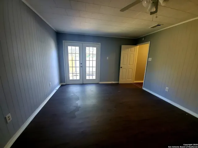 an empty room with wooden floor and windows with curtains