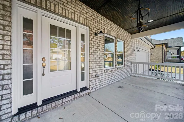 an empty room with wooden floor chandelier fan and windows