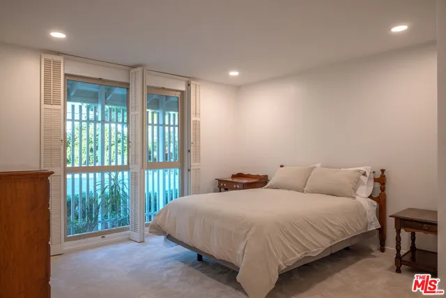 a bedroom with a balcony a bed and a large window