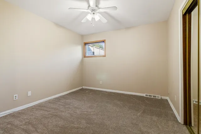 an empty room with a window and a fan
