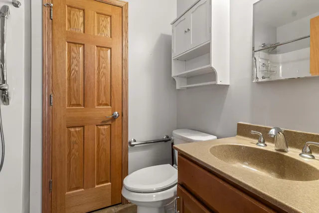a bathroom with a granite countertop toilet sink and mirror