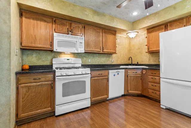 a kitchen with granite countertop wooden cabinets and white appliances