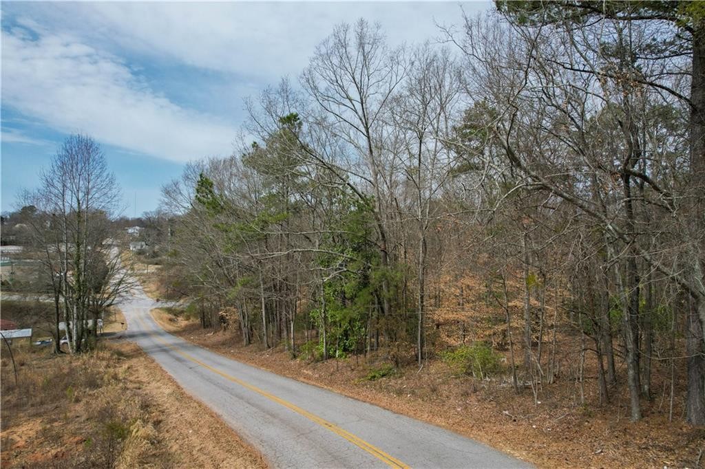 0 North Walnut Street Seneca, SC 29678 - Photo 11 of 12 A tranquil, tree-lined road winds through a peaceful wooded landscape, inviting serene drives.