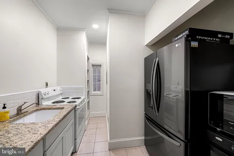 a kitchen with granite countertop a refrigerator stove and sink