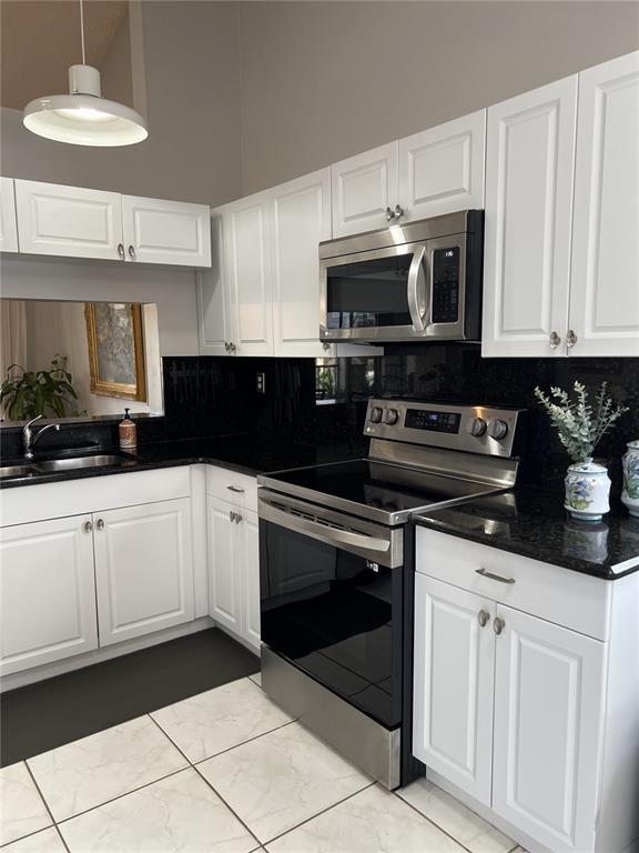 18266 Covina Way, Unit 202 Boca Raton, FL 33498 - Photo 15 of 52 a kitchen with white cabinets and black appliances