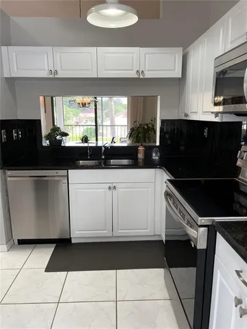 a kitchen with granite countertop white cabinets and black stainless steel appliances