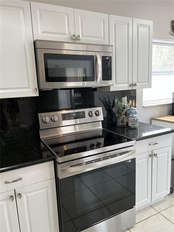 18266 Covina Way, Unit 202 Boca Raton, FL 33498 - Photo 17 of 52 a kitchen with granite countertop white cabinets and black stainless steel appliances