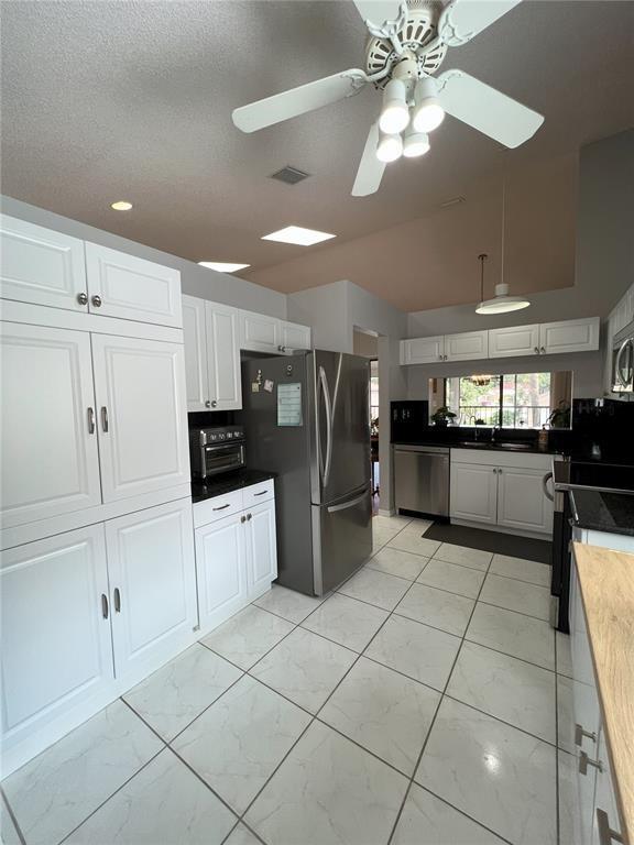 18266 Covina Way, Unit 202 Boca Raton, FL 33498 - Photo 19 of 52 a kitchen with stainless steel appliances kitchen island granite countertop a refrigerator and a stove top oven