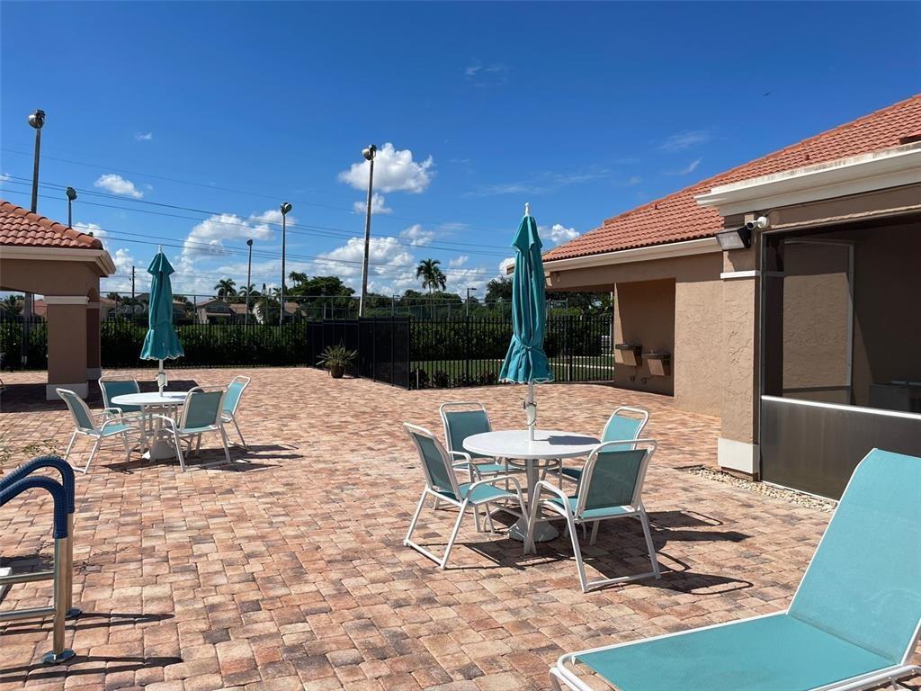 18266 Covina Way, Unit 202 Boca Raton, FL 33498 - Photo 47 of 52 a view of a patio with a dining table and chairs with wooden floor