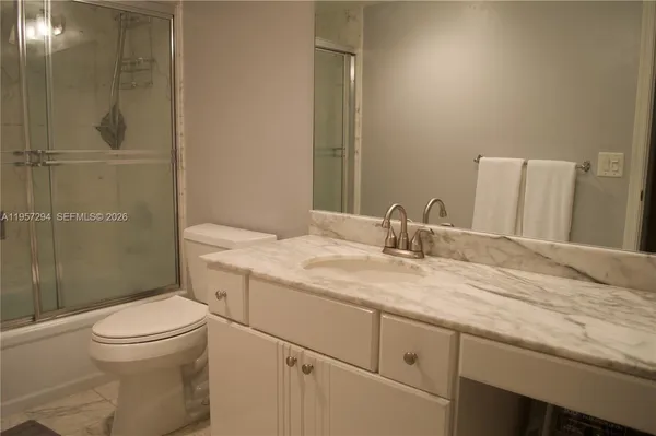 a bathroom with a granite countertop sink a toilet and shower