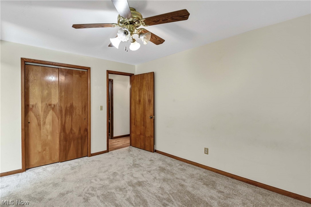 301 Crosse Road Amherst, OH 44001 - Photo 28 of 49 Carpeted room featuring a ceiling fan with light fixture, wooden bi-fold closet doors, a wooden door frame, and white painted walls