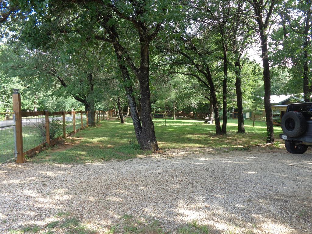 5525 Cedar Oaks Road Grandview, TX 76050 - Photo 24 of 40 Gravel drive with a partial wood and wire fence, mature trees, and a grassy expanse