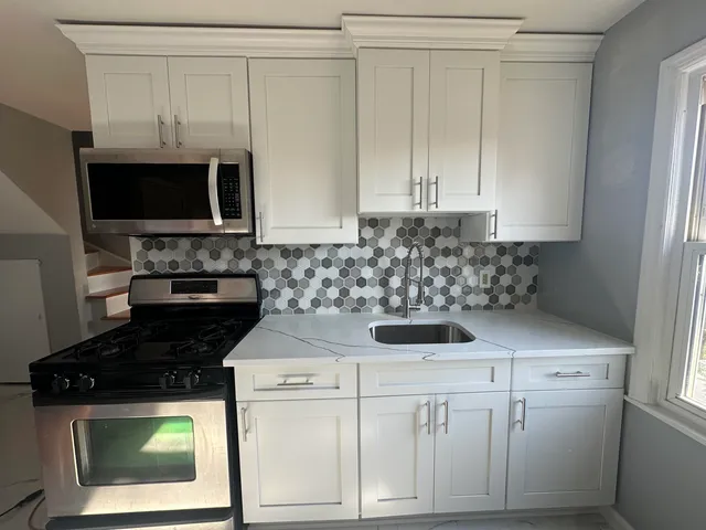 a kitchen with white cabinets and black appliances