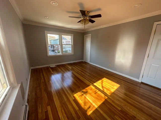 a view of empty room with wooden floor and fan