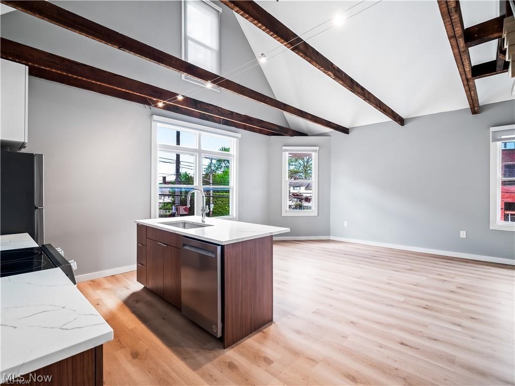 2401 Scranton Road, Unit A Cleveland, OH 44113 - Photo 7 of 17 Open-concept living space featuring vaulted ceilings with exposed wood beams, light wood-finish flooring, and multiple windows