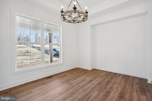 an empty room with wooden floor and fan