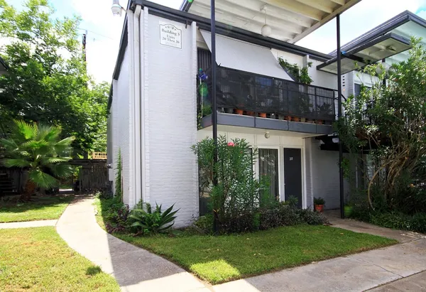 a view of a house with brick walls plants and large tree