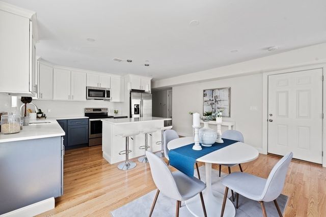 a kitchen with white cabinets stainless steel appliances and dining table