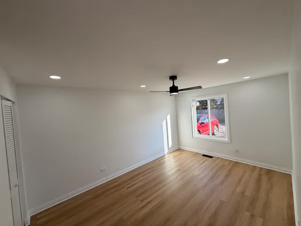 an empty room with wooden floor and ceiling fan