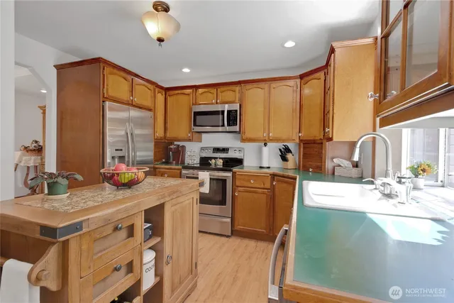 a kitchen with stainless steel appliances granite countertop a sink a stove and a refrigerator