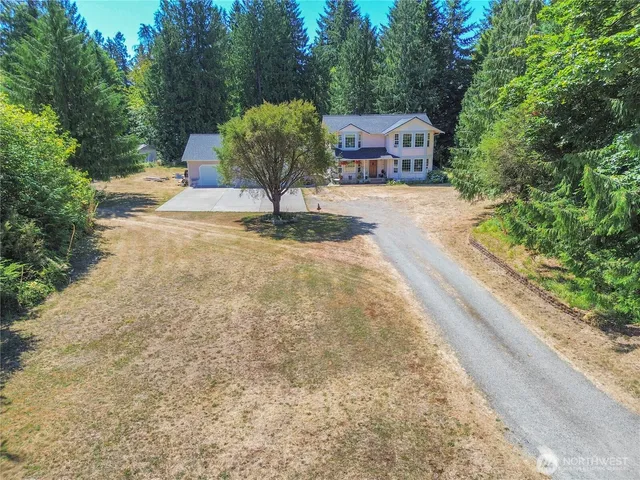 a pathway of a house with a yard and large trees