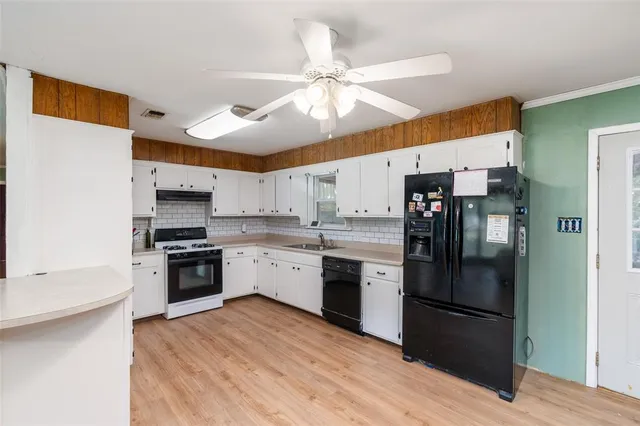 a kitchen with stainless steel appliances granite countertop a refrigerator a sink dishwasher a stove and a refrigerator with wooden floor