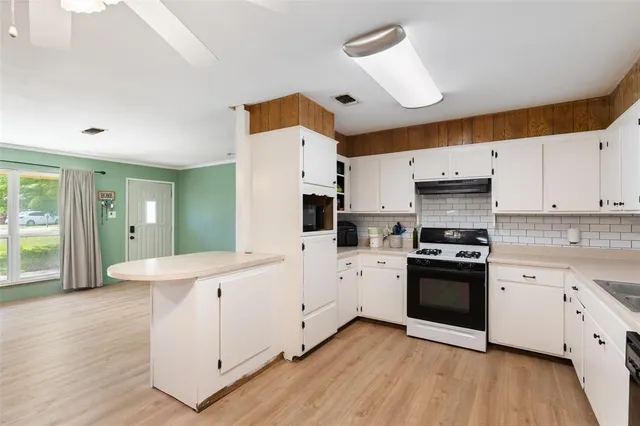 a kitchen with stainless steel appliances a sink stove and wooden floor