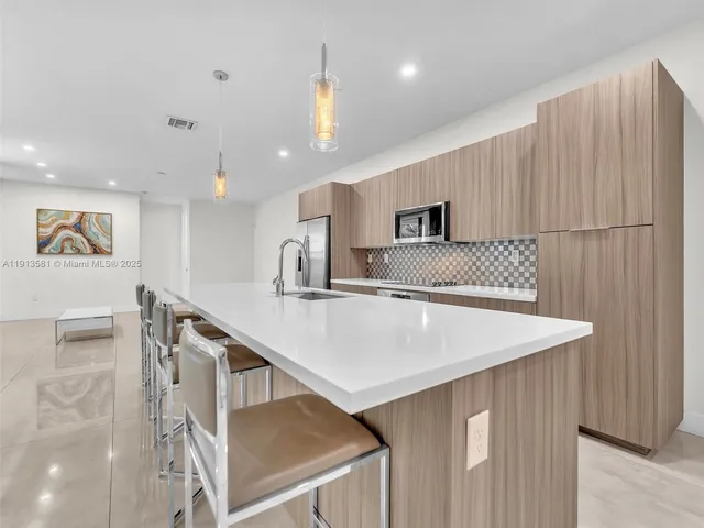 a large kitchen with stainless steel appliances kitchen island granite countertop a sink and cabinets