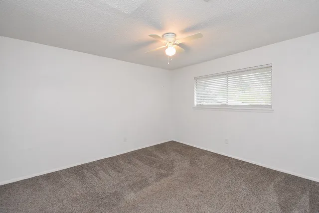 an empty room with a chandelier fan and windows