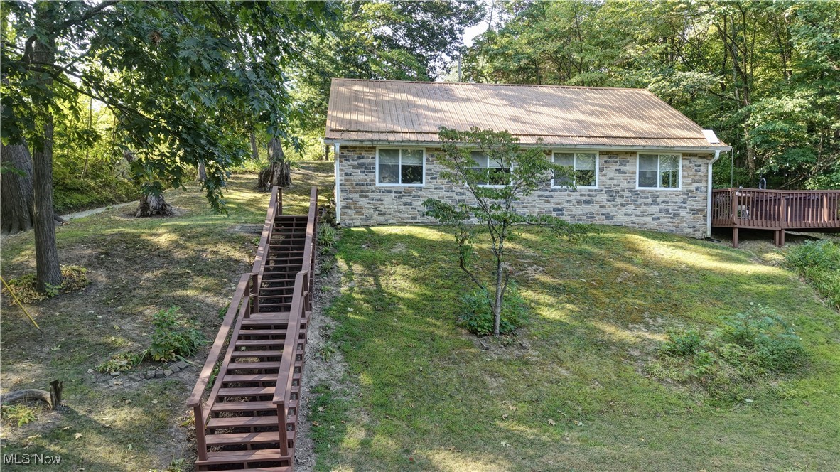 2227 Elk Road Southwest Carrollton, OH 44615 - Photo 4 of 40 View of front of house with stone siding, stairs, a wooden deck, and a metal roof