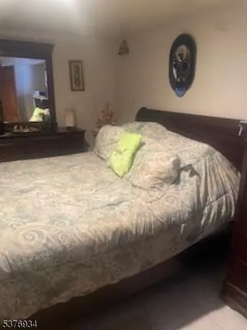 a bedroom with a bed and a lamp on dresser
