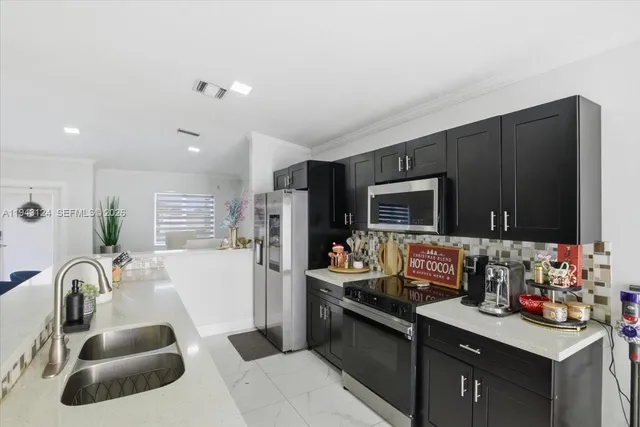 a kitchen with stainless steel appliances granite countertop a sink and a refrigerator