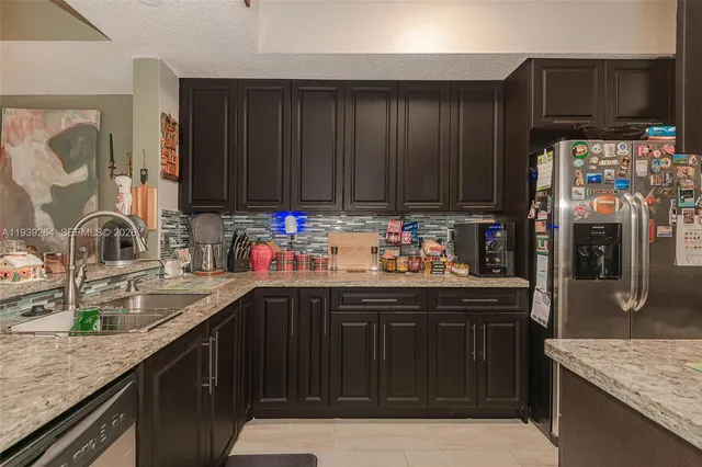 a kitchen with granite countertop a refrigerator stove and sink