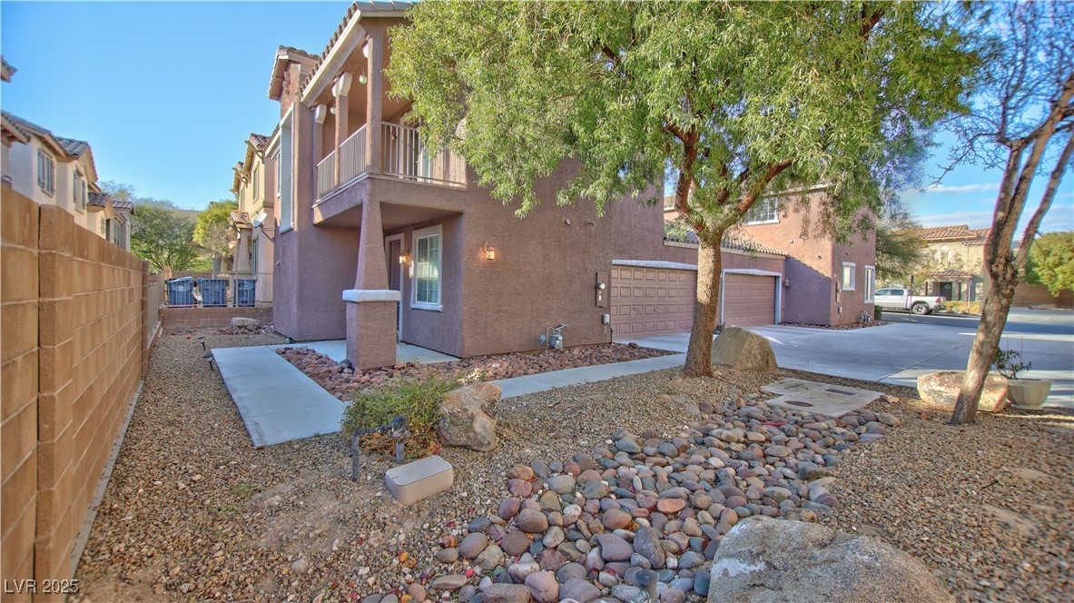 View of side of property featuring stucco siding, concrete driveway, and a balcony