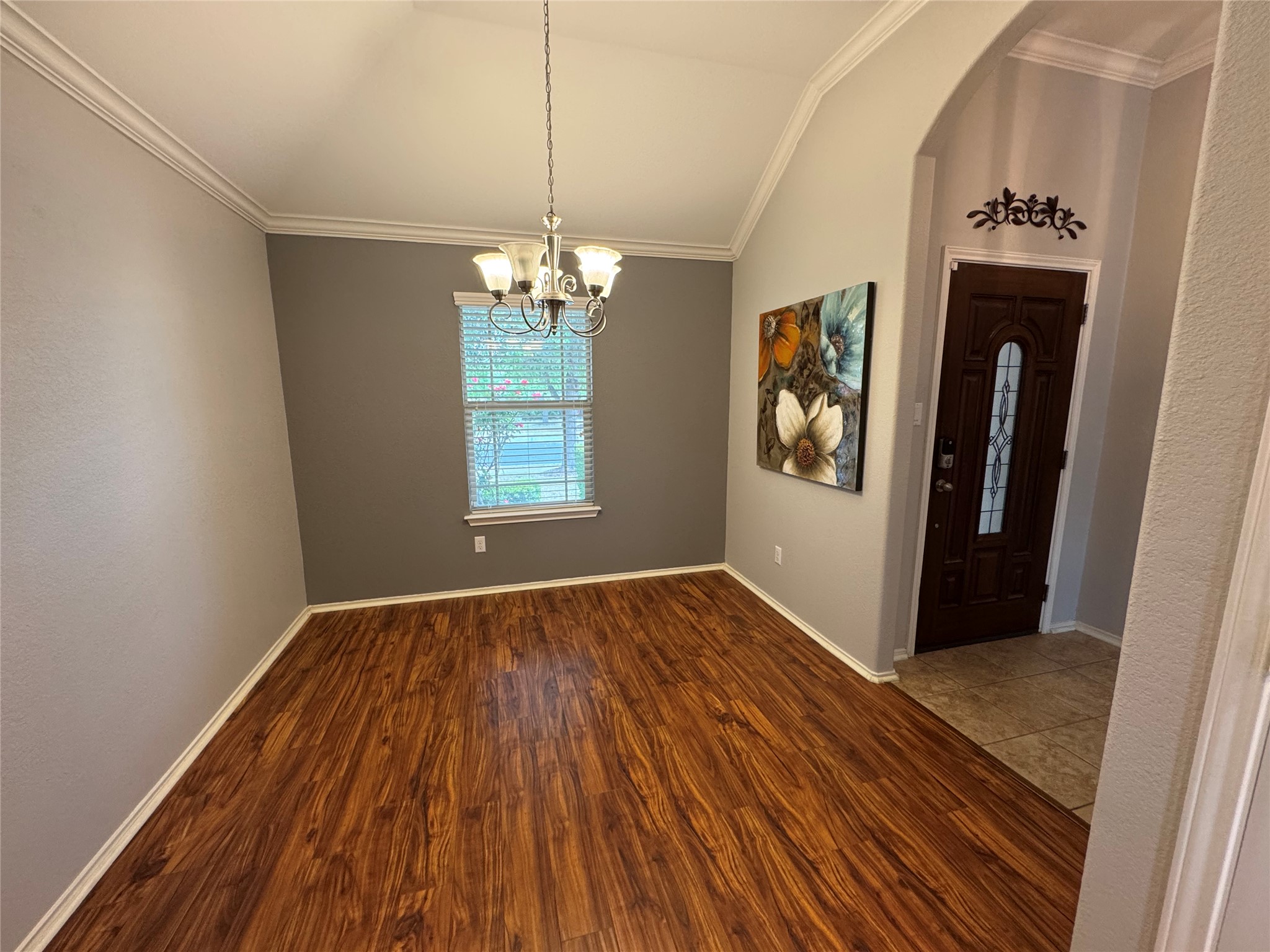 112 Eagle Owl Loop Leander, TX 78641 - Photo 4 of 17 Entrance foyer featuring ornamental molding, vaulted ceiling, dark wood-style floors, a chandelier, and arched walkways