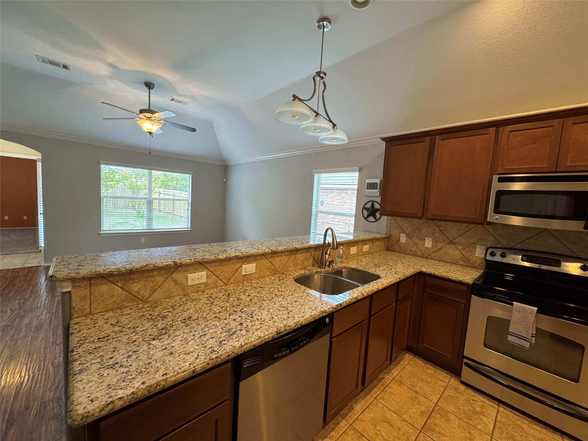112 Eagle Owl Loop Leander, TX 78641 - Photo 6 of 17 Kitchen with stainless steel appliances, a peninsula, light stone counters, a ceiling fan, and lofted ceiling