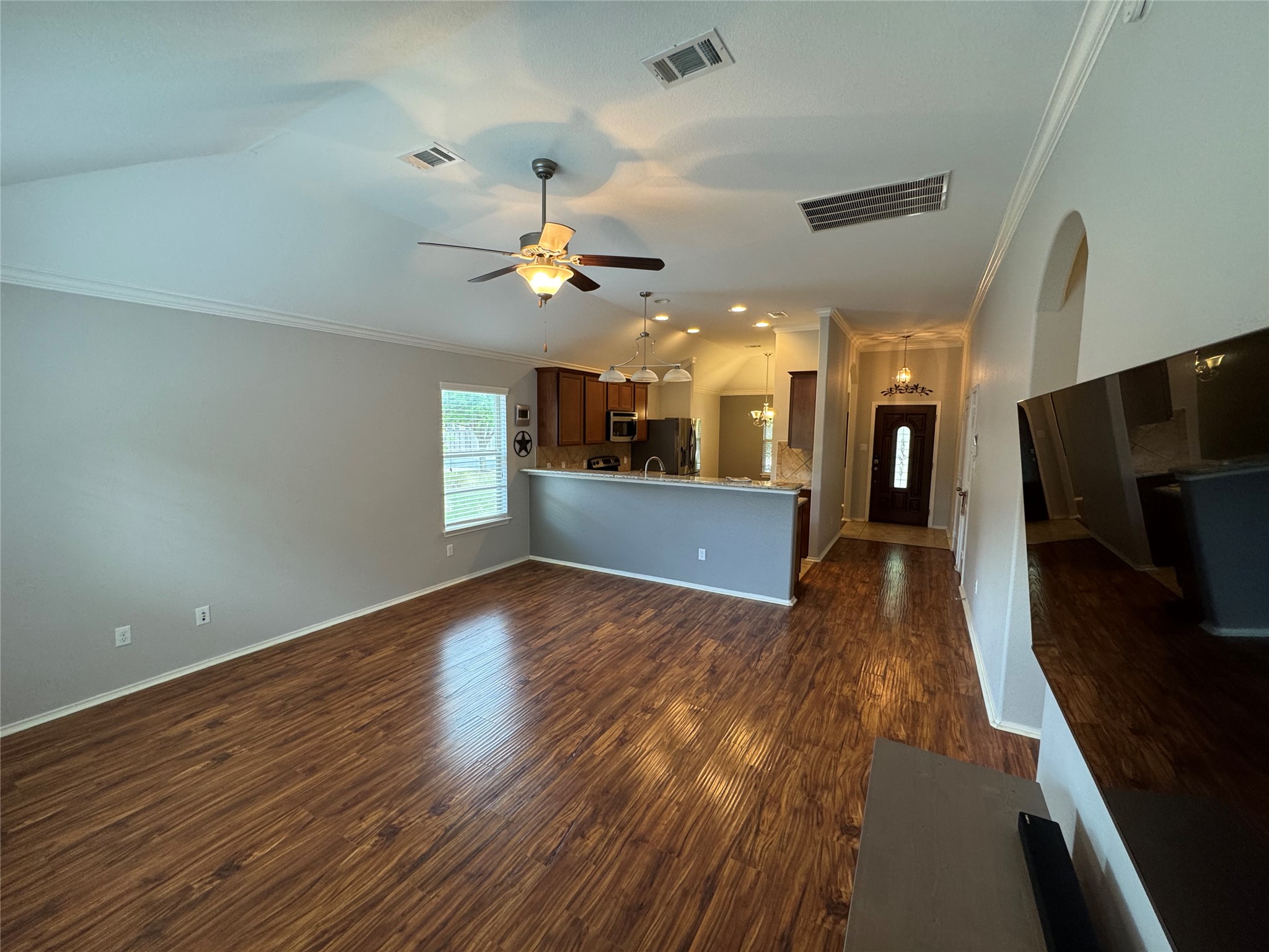 112 Eagle Owl Loop Leander, TX 78641 - Photo 7 of 17 Unfurnished living room with ornamental molding, dark wood finished floors, ceiling fan, vaulted ceiling, and arched walkways