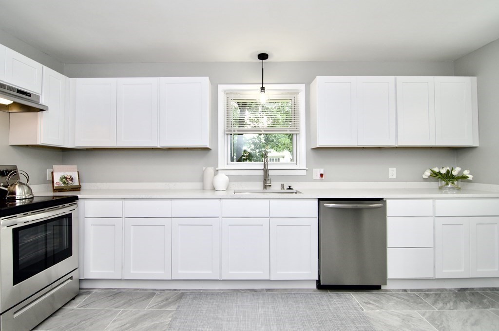 a kitchen with white cabinets white stainless steel appliances and sink