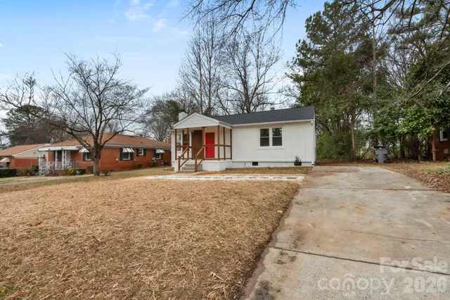 a front view of a house with a yard and large trees