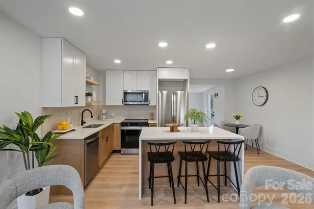 a kitchen with stainless steel appliances granite countertop a table chairs sink and cabinets