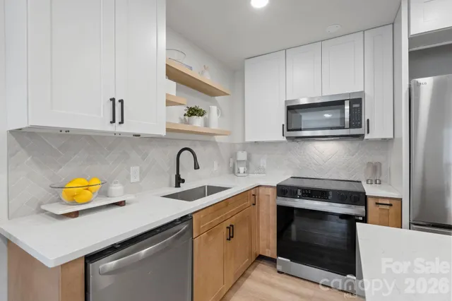 a kitchen with stainless steel appliances a stove a microwave a sink cabinets and a counter space