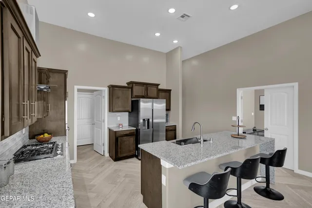 a kitchen with stainless steel appliances kitchen island granite countertop a sink and a refrigerator
