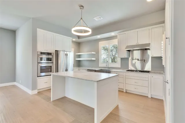 a kitchen with stainless steel appliances a stove refrigerator and cabinets