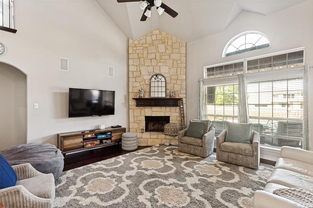 4117 Autumn Path Road Denton, TX 76208 - Photo 2 of 14 Vaulted living space featuring a stone fireplace with a dark wood mantle, wood-finish flooring, and a large arched window