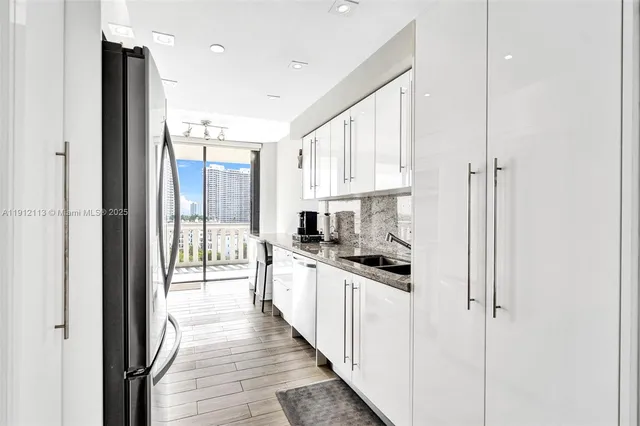 a kitchen with stainless steel appliances a refrigerator sink and white cabinets